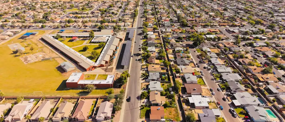 An Arizona neighborhood seen from the air, with single-story houses along a straight street and a mountain ridge on the horizon